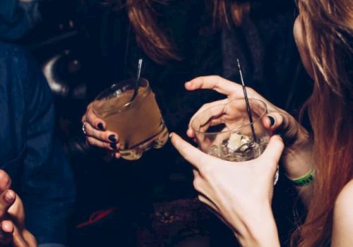 People are enjoying drinks at a party, laughing and socializing.