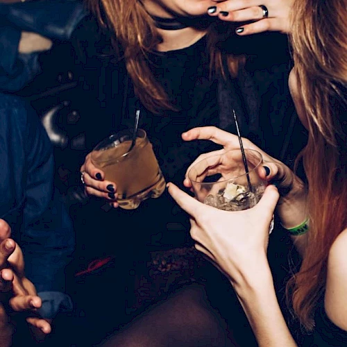 People are enjoying drinks at a party, laughing and socializing.