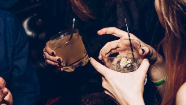 People are enjoying drinks at a party, laughing and socializing.