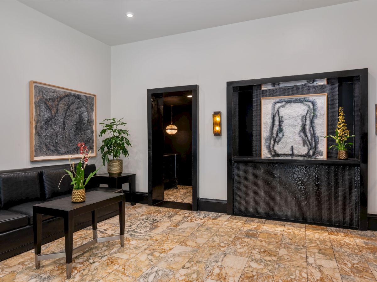 A modern room with abstract art, seating with a table, plants, and stone flooring. The design is minimalistic with a calming vibe.
