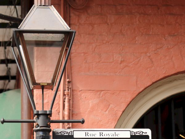 A street sign reading "Royal" is mounted on a pole with a vintage lamp, set against a red brick building backdrop.