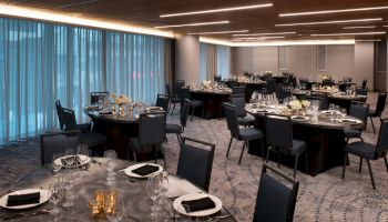 A modern banquet hall with round tables set for a formal event and dim lighting creates an elegant atmosphere.