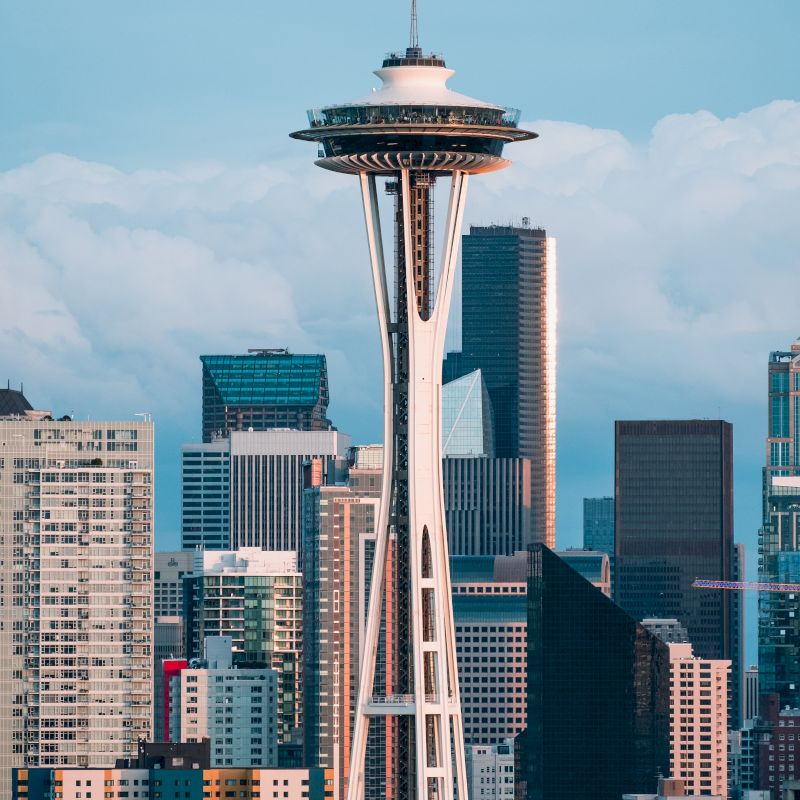 The image shows a city skyline with a prominent tower in the foreground, surrounded by various skyscrapers and buildings.
