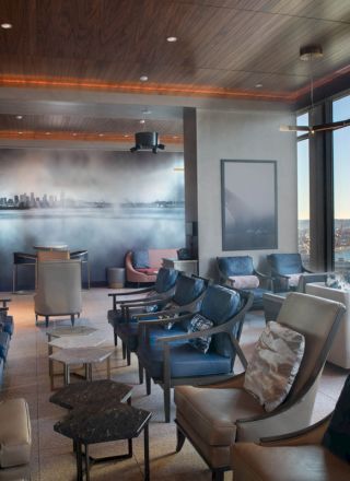 A modern lounge with plush seating, large windows offering a scenic view of a ferris wheel and water, and ambient lighting in a cozy setting.