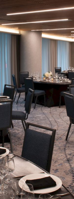 A banquet hall set up with round tables, elegant place settings, and flower centerpieces, ready for an event or dinner.