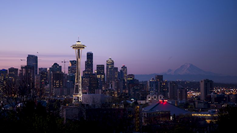 Seattle skyline at dusk with the Space Needle, city buildings, and Mount Rainier in the background creating a picturesque view.